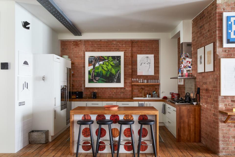 In the simple wood-and-white kitchen, Tovey has enlivened the space under the breakfast bar with a wallpaper by artist Jonas Wood. Tovey jokes that if he didn’t keep his hoarding tendencies in check, the whole apartment would look like the extractor—awash with mementoes. To the left a work by Leon Polk Smith sits under an Alexander Girard bird relief for Vitra. To the right of the extractor hang two works on paper by Kara Walker.