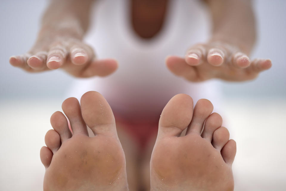 A woman stretching her arms out to touch her toes in a forward motion