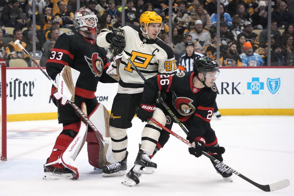 Pittsburgh Penguins' Sidney Crosby (87) screens Ottawa Senators goaltender Cam Talbot (33) with Erik Brannstrom (26) defending during the second period of an NHL hockey game in Pittsburgh, Friday, Jan. 20, 2023. (AP Photo/Gene J. Puskar)