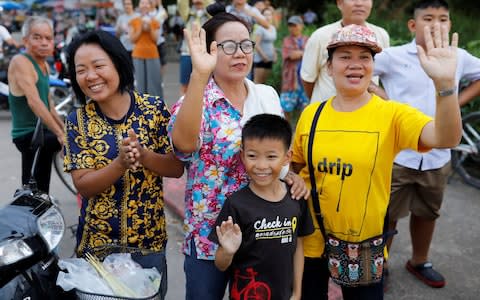 Onlookers wave as an ambulance carrying rescued schoolboys leaves a military airport in Chiang Rai - Credit: TYRONE SIU /Reuters