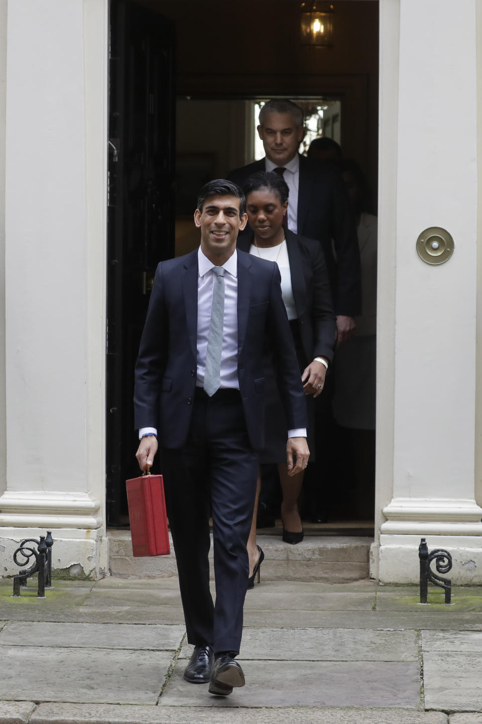 Britain's Chancellor of the Exchequer Rishi Sunak walks from No 11 Downing Street as he holds the traditional red box that contains the budget speech for the media, he will then leave to make budget speech to House of Commons, in London, Wednesday, March 11, 2020. Britain's Chancellor of the Exchequer Rishi Sunak will announce the first budget since Britain left the European Union. (AP Photo/Kirsty Wigglesworth)