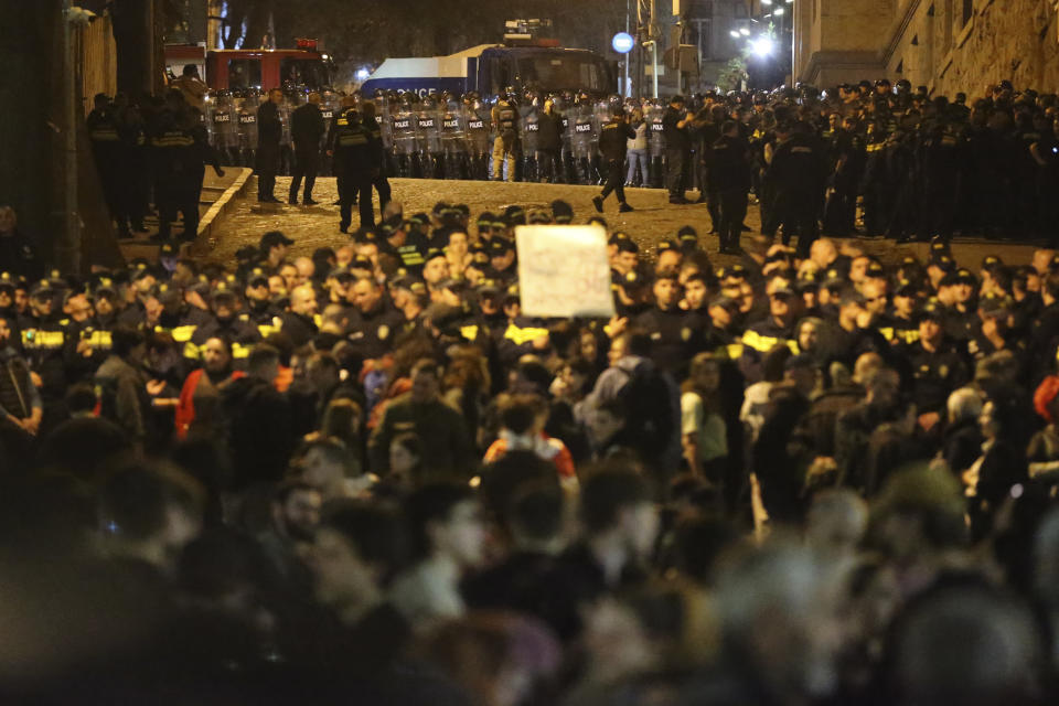 Police officers block protestors as they gather outside the parliament building in Tbilisi, Georgia, on Tuesday, April 16, 2024, to protest against "the Russian law" similar to a law that Russia uses to stigmatize independent news media and organizations seen as being at odds with the Kremlin. (AP Photo/Zurab Tsertsvadze)