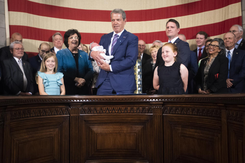 Nebraska Gov. Jim Pillen smiles as he holds newborn Gemma Pond next to his granddaughters, Eloise Pillen, left, and Halle Trouba, at the signing of LB 574, Monday, May 22, 2023, in Lincoln, Neb. (Justin Wan/Lincoln Journal Star via AP)