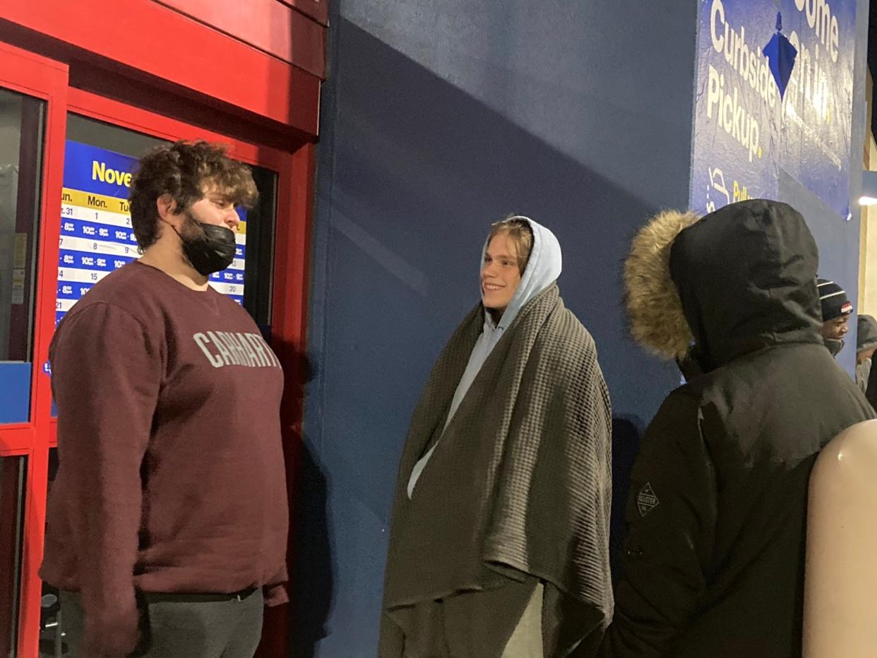 Eli Higgins, center, talks with Carter Eads, far left, outside of Best Buy in Springfield just after 4 a.m. Friday. Higgins and Larson, along with Maxwell Larson, far right, were first in line for the store's 5 a.m. opening.