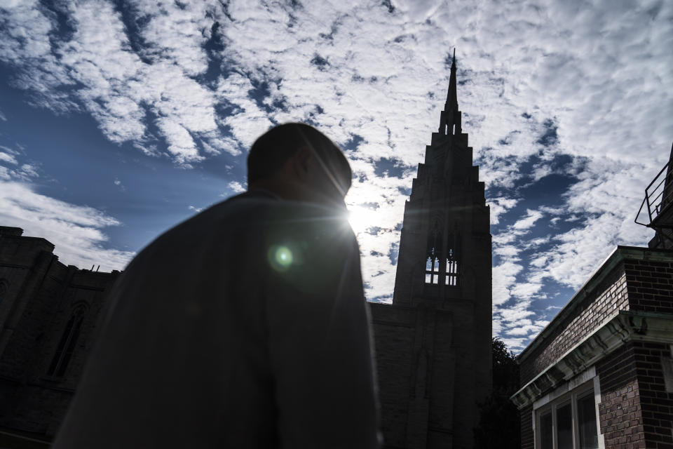 The steeple of Asbury First United Methodist Church stands in the background as Rev. Stephen Cady walks on the campus, Tuesday, Aug. 22, 2023, in Rochester, N.Y. After mass shootings at houses of worship, Asbury’s security committee has conferred with local police, updated the church’s emergency plans and worked to secure the premises. But they have decided against arming guards or others. (AP Photo/David Goldman)