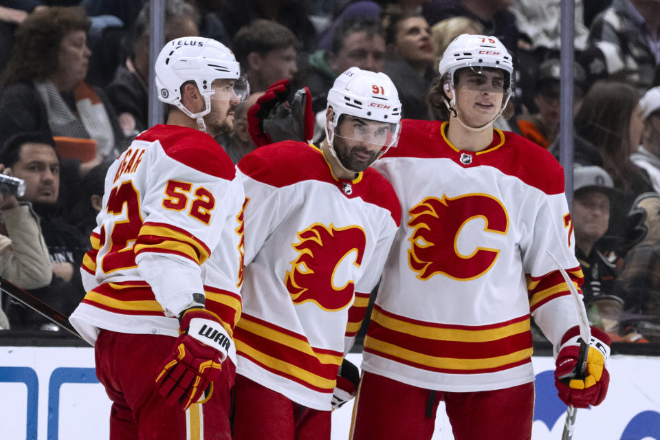 Calgary Flames center Nazem Kadri (91) celebrates his goal against the Anaheim Ducks with defenseman MacKenzie Weegar (52) and center Martin Pospisil (76) during the first period of an NHL hockey game Friday, April 12, 2024, in Anaheim, Calif. (AP Photo/Kyusung Gong)