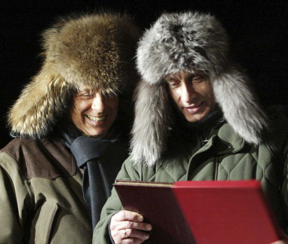 FILE - Russian President Vladimir Putin, right, presents a book about his rural lodge Zavidovo to former Italian Prime Minister Silvio Berlusconi in Zavidovo, about 120 kilometers (75 miles) northwest of Moscow, on Feb. 3, 2003. Berlusconi, the boastful billionaire media mogul who was Italy's longest-serving premier despite scandals over his sex-fueled parties and allegations of corruption, died, according to Italian media. He was 86. (AP Photo/Viktor Korotayev, Pool, File)