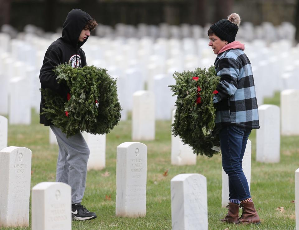 Ellen Hildenbrand and her son, Simon, placed wreaths at gravesites.  About a thousand volunteers teamed up to place 6000 wreaths at the graves of soldiers buried at Zachary Taylor National Cemetery on Saturday, December 17, 2022