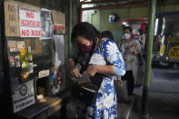 A woman holds her vaccination card before riding a passenger jeep at a terminal in Quezon city, Philippines on Monday, Jan. 17, 2022. People who are not fully vaccinated against COVID-19 were banned from riding public transport in the Philippine capital region Monday in a desperate move that has sparked protests from labor and human rights groups. (AP Photo/Aaron Favila)