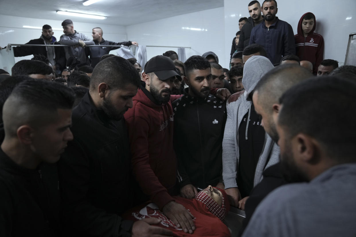 Palestinian mourners gather around the body of Omar Manaa during his funeral in the West Bank refugee camp of Deheishe near the city of Bethlehem, Monday, Dec. 5, 2022. Palestinian health officials say a 22-year-old Palestinian man has been killed by Israeli fire during a military raid in the occupied West Bank. The army said it opened fire after a crowd attacked soldiers with stones and firebombs. (AP Photo/Mahmoud Illean)