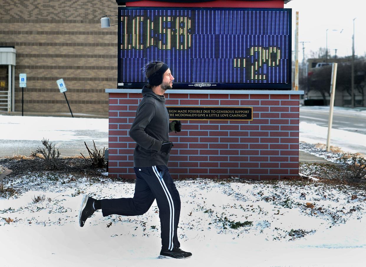 Nick Coffman of Austin, Texas jogs past the Ronald McDonald House sign at the corner of Carpenter and 7th streets showing a temperature of -2 to degrees Friday. Coffman grew up in Springfield and was visiting family for the holidays.