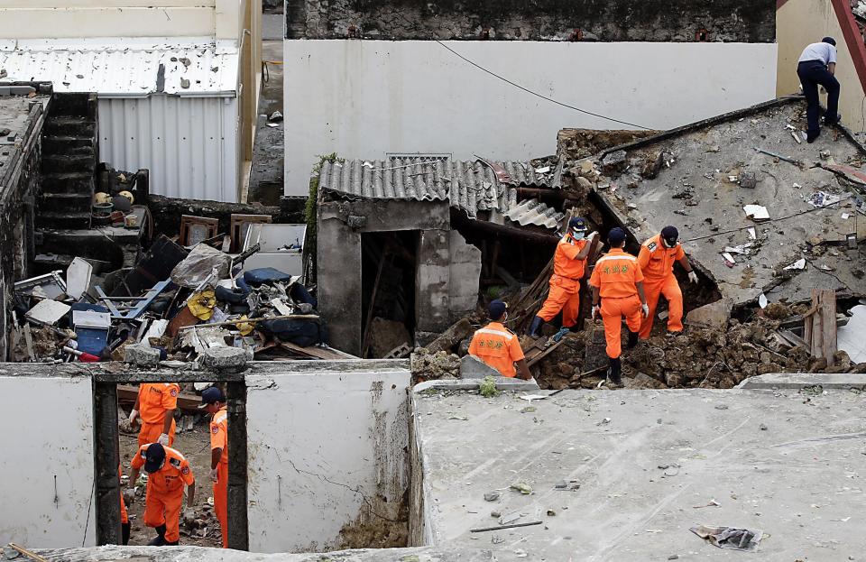 Rescue personnel survey the wreckage of a TransAsia Airways turboprop plane that crashed, on Taiwan's offshore island Penghu July 24, 2014. The leaders of rivals China and Taiwan expressed condolences on Thursday for victims of the plane that crashed during a thunderstorm the previous day killing 48 people including two French nationals. (REUTERS/Pichi Chuang)