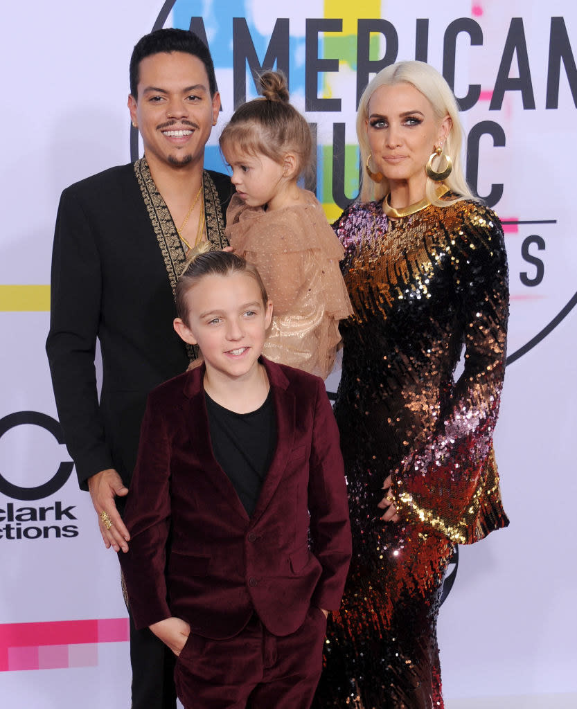 Evan Ross wears a dark v-neck blazer, Bronx Wentz wears a dark velvet suit, Jagger Toss wears a light colored dress, and Ashlee Simpson Ross wears a long sleeve sparkly gown