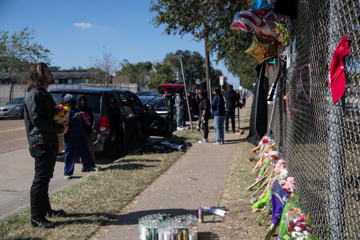 Ian James clasps a flower bouquet and reads notes written on a growing memorial in front of NRG Park on Nov. 7, 2021, in Houston. James was in the front row of the Travis Scott set at Astroworld Festival.