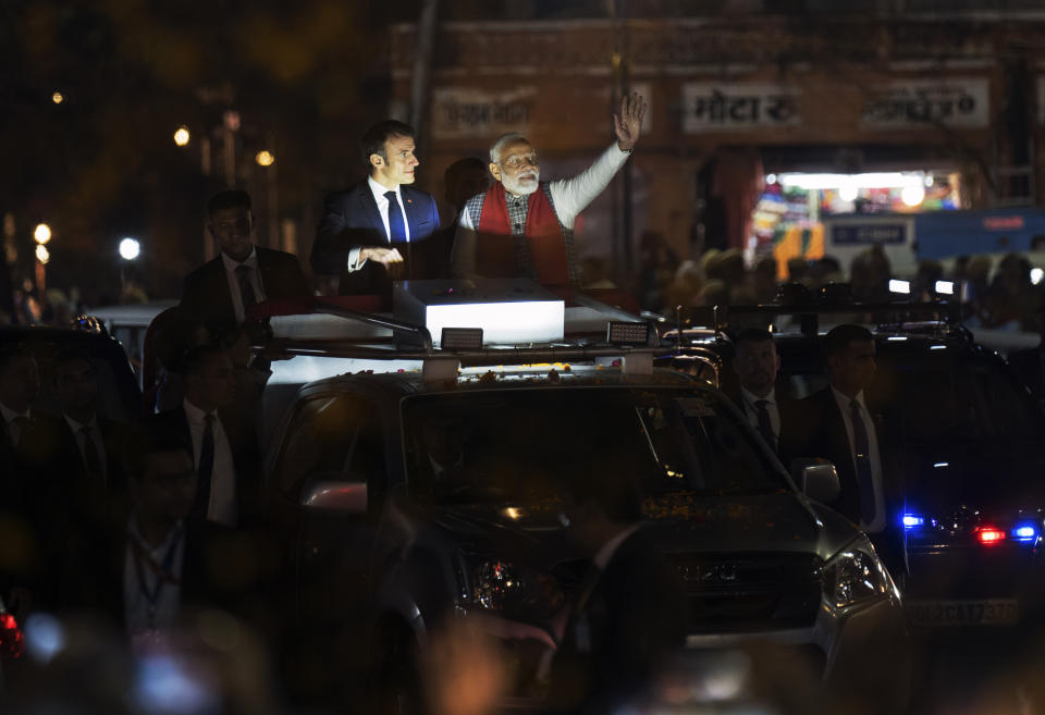 French President Emmanuel Macron, left, and Indian Prime Minister Narendra Modi, with his arm outstretched, ride an open vehicle together during a road show in Jaipur, Rajasthan, India, Thursday, Jan. 25, 2024. Macron will be the chief guest at India's annual republic day parade in New Delhi on Friday. (AP Photo/ Deepak Sharma)