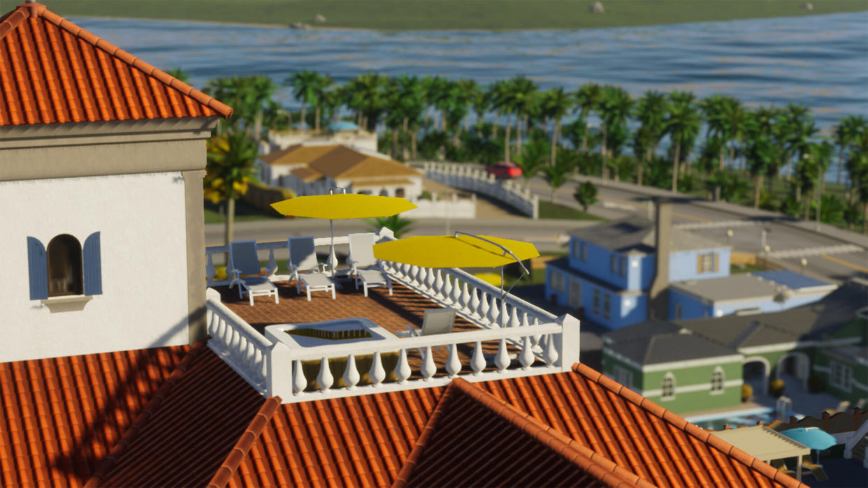  Cities: Skylines 2 Beach Properties screenshot - balcony with beach chairs and umbrellas overlooking a street running beside a palm tree-lined coast. 