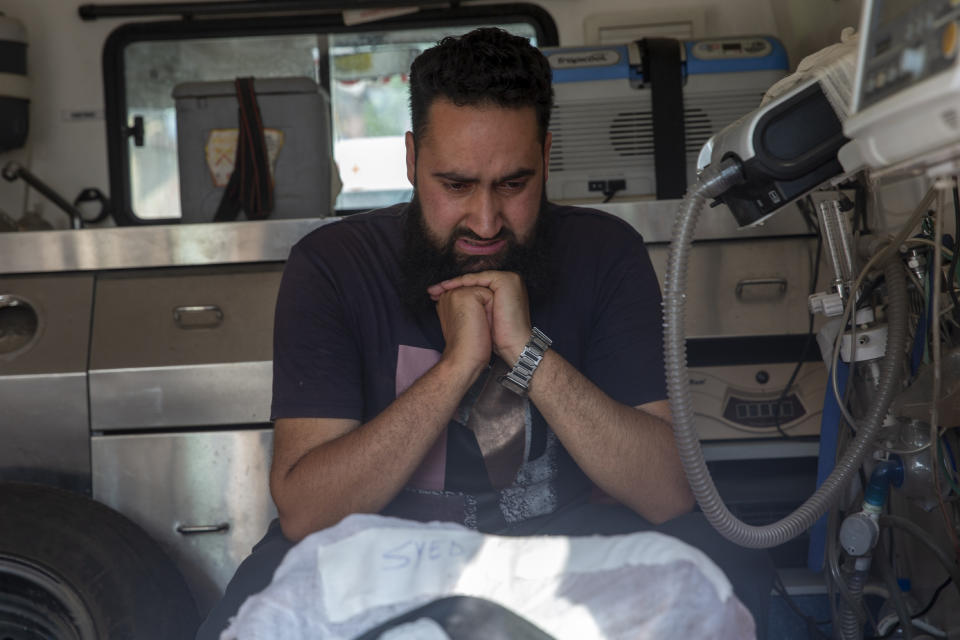 A man grieves besides bodies of a politician Sheikh Wasim Bari and his brother, inside an ambulance in Bandipora town, north of Srinagar, Indian controlled Kashmir, Thursday, July 9, 2020. Unidentified assailants late Wednesday fatally shot Bari, a leader with Prime Minister Narendra Modi's Bharatiya Janata Party, along with his father and brother in Kashmir, police said, in a first major attack against India's ruling party members in the disputed region. (AP Photo/ Dar Yasin)