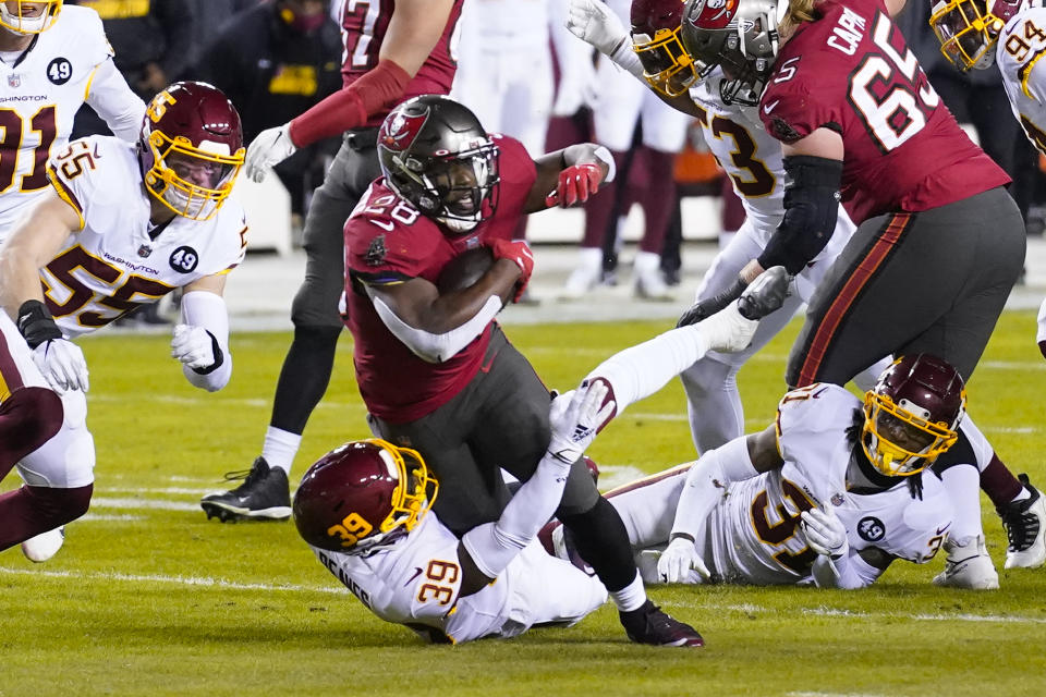 Tampa Bay Buccaneers running back Leonard Fournette (28) is taken down by Washington Football Team free safety Jeremy Reaves (39) during the first half of an NFL wild-card playoff football game, Saturday, Jan. 9, 2021, in Landover, Md. (AP Photo/Andrew Harnik)