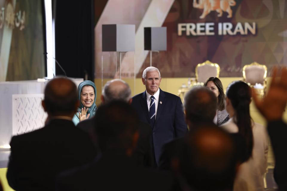 Former U.S. Vice President Mike Pence, center, and the leader of the People's Mujahedin of Iran Maryam Rajavi, left, wave to the participants at the Iranian opposition headquarters in Albania, where up to 3,000 MEK members reside at Ashraf-3 camp in Manza town, about 30 kilometers (16 miles) west of Tirana, Albania, Thursday, June 23, 2022. (AP Photo/Franc Zhurda)