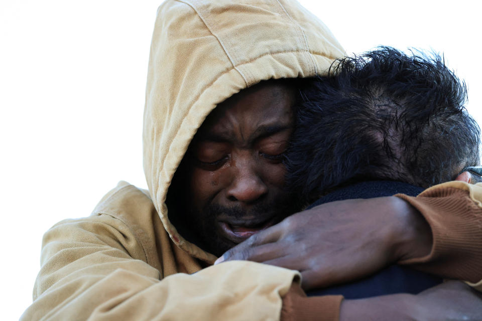 Joshua Thurman, left, in hooded jacket, embraces another mourner.