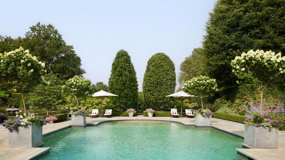 a pool with trees and chairs around it