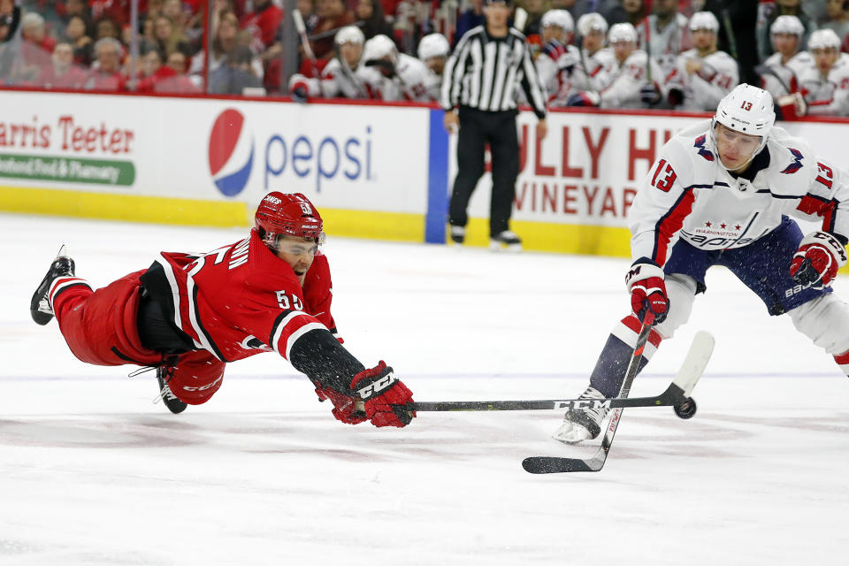 Carolina Hurricanes' Roland McKeown (55) dives to tip the puck away from Washington Capitals' Jakub Vrana (13), of the Czech Republic, during the third period of an NHL preseason hockey game in Raleigh, N.C., Sunday, Sept. 29, 2019. (AP Photo/Karl B DeBlaker)