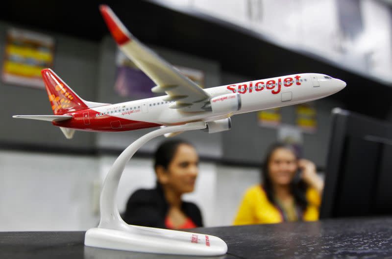 Employees work inside a travel agency office besides a model of a SpiceJet aircraft in Ahmedabad