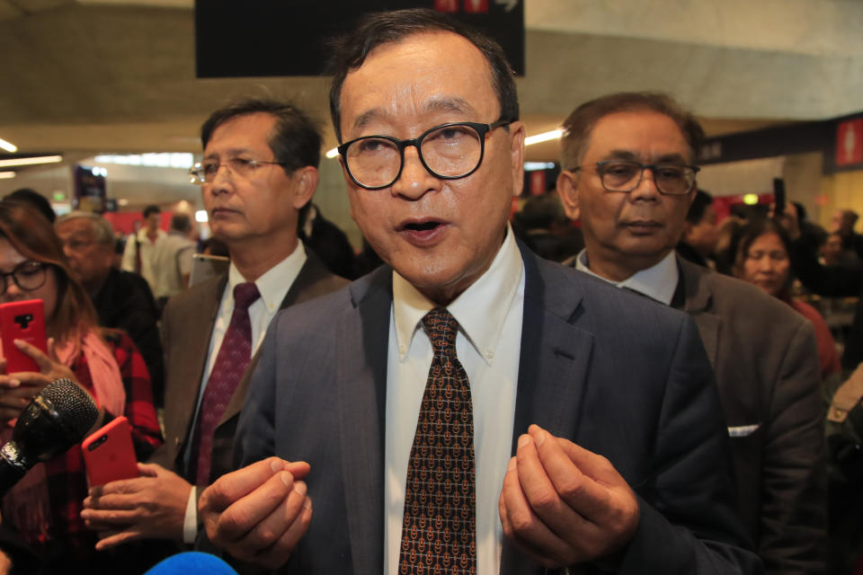 Cambodia's most prominent opposition politician Sam Rainsy answers reporters as he is attempting to return to Cambodia Thursday, Nov. 7, 2019 at Charles de Gaulle airport, north of Paris. Sam Rainsy is attempting to return to Cambodia from his self-imposed exile to force out the long-serving leadership but may not be let on Thursday's Paris-Bangkok flight. (AP Photo/Michel Euler)