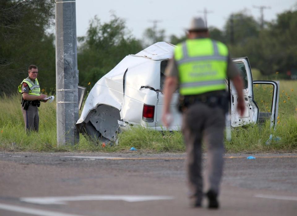 Texas Department of Public Safety officers pick up debris near a vehicle where multiple people died after the van carrying migrants tipped over just south of the Brooks County community of Encino on Wednesday, Aug. 4, 2021, in Encino, Texas.