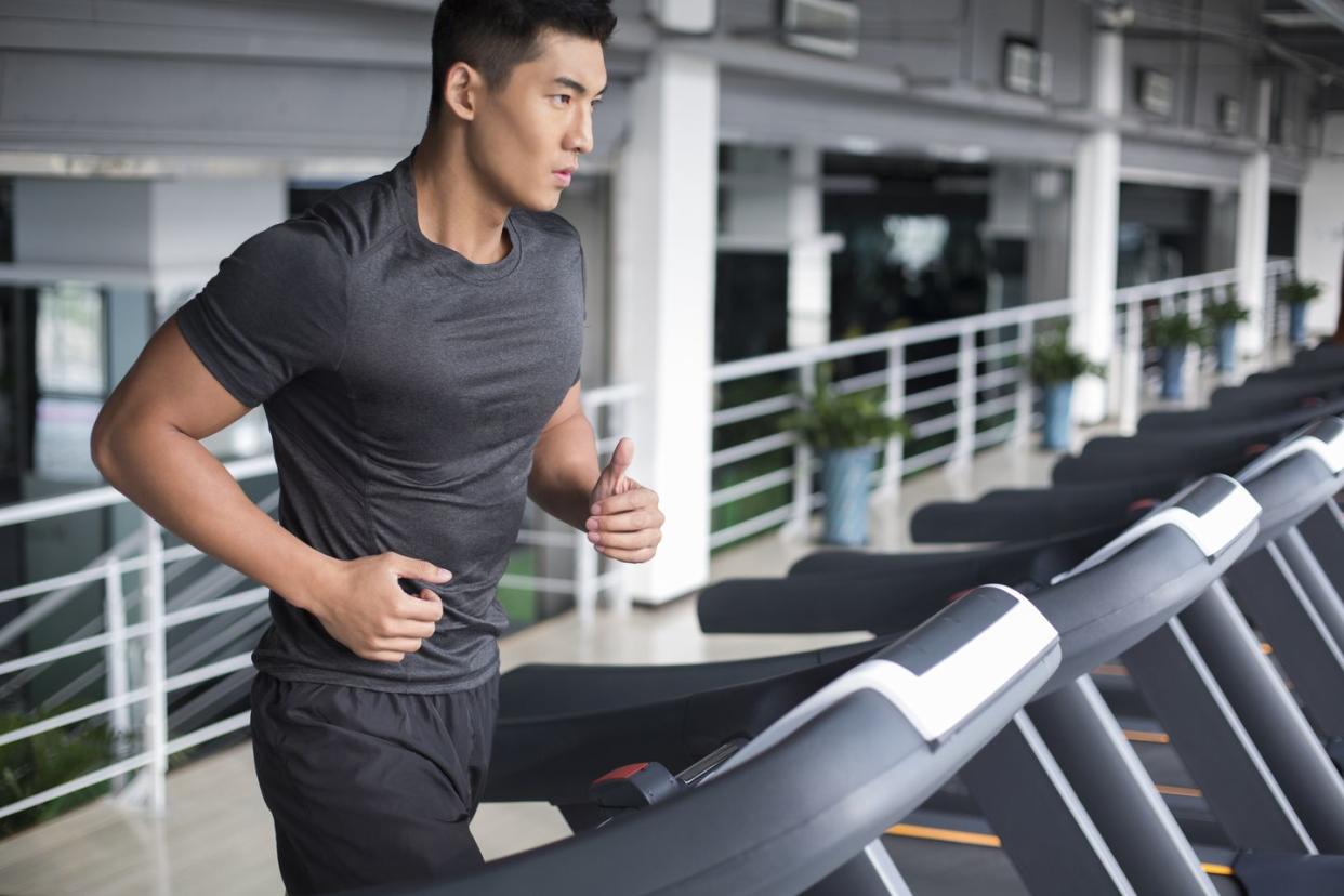 young man running on treadmill in gym