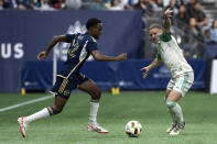 Vancouver Whitecaps' Ali Ahmed, left, runs with the ball as Austin FC's Alexander Ring (8) defends during the first half of an MLS soccer match in Vancouver, British Columbia, on Saturday, May 4, 2024. (Ethan Cairns/The Canadian Press via AP)