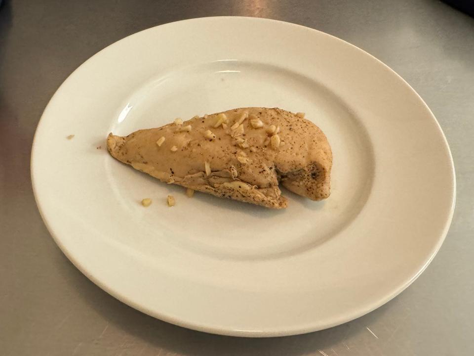 sous vide chicken breast on a while plate in front of someone