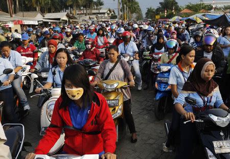 Workers of a shoe factory on their motorcycles are stuck in a traffic jam as they make their home after work, at Pasar Kemis industrial park in Tangerang August 14, 2014. REUTERS/Beawiharta