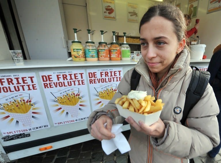 A woman eats fries with mayonnaise in Leuven, Belgium. Fries, crunchy, salty, tasty fried sticks of potato are claimed by Belgium and France as the product of their national gastronomic genius but the true origins are shrouded in popular folklore