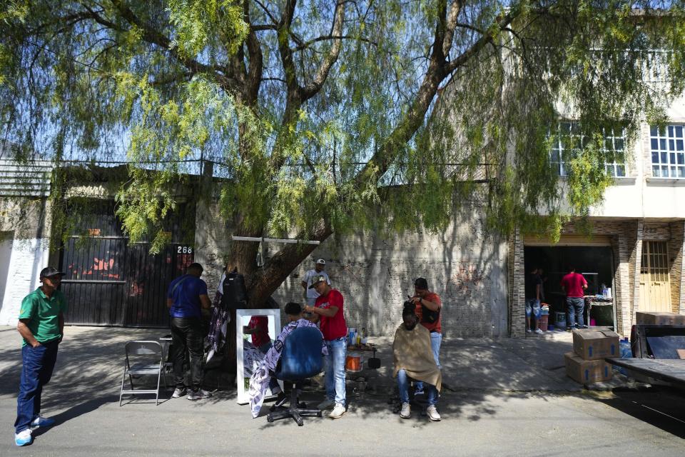 Migrantes venezolanos se cortan el pelo junto a las vías del tren bordeadas por tiendas de campaña improvisadas en la Ciudad de México, el martes 26 de marzo de 2024. (AP Foto/Fernando Llano)