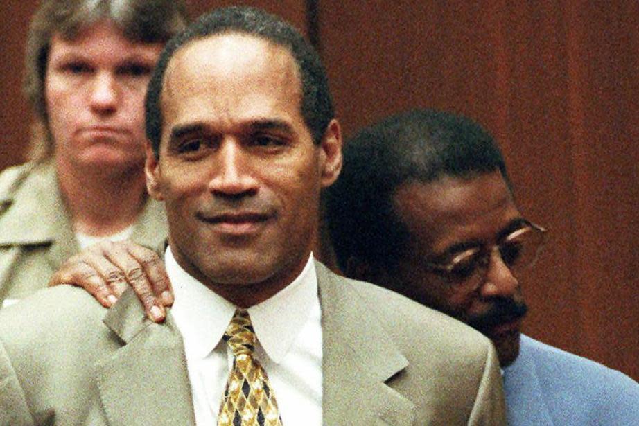Attorney Johnnie Cochran holds OJ Simpson as the 'not guilty' verdict is read out at his 1995 murder trial (AP)