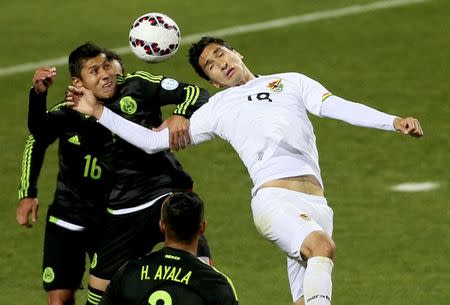 Bolivia's Ricardo Pedriel has his arm held by Mexico's Julio Dominguez as Mexico's Hugo Ayala looks on as they go up for the ball during their first round Copa America 2015 soccer match at Estadio Sausalito in Vina del Mar, Chile, June 12, 2015. REUTERS/Rodrigo Garrido