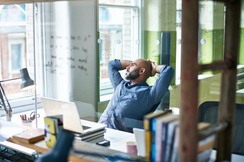 A man leans back from his desk