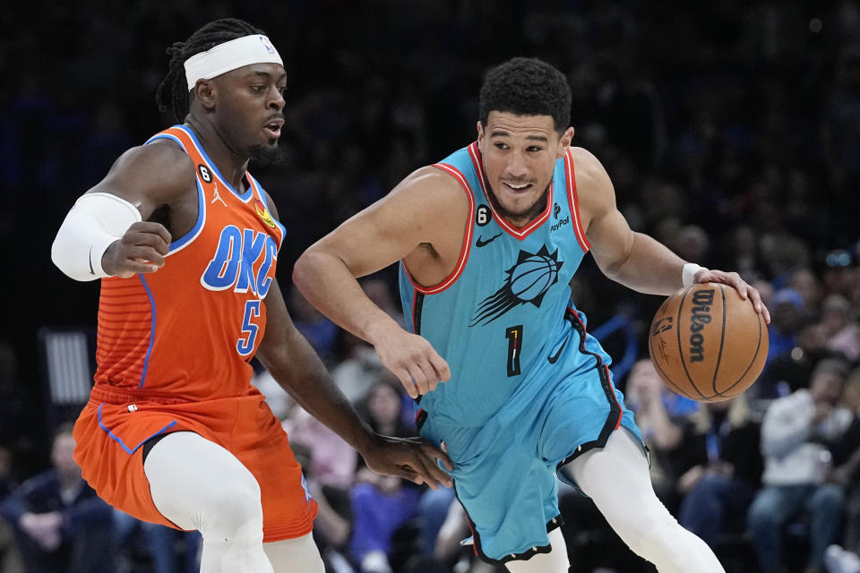 Phoenix Suns guard Devin Booker (1) drives against Oklahoma City Thunder guard Luguentz Dort (5) in the second half of an NBA basketball game Sunday, March 19, 2023, in Oklahoma City. (AP Photo/Sue Ogrocki)