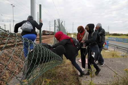 Migrants make their way across a fence near near train tracks as they attempt to access the Channel Tunnel in Frethun, near Calais, France, July 29, 2015. REUTERS/Pascal Rossignol