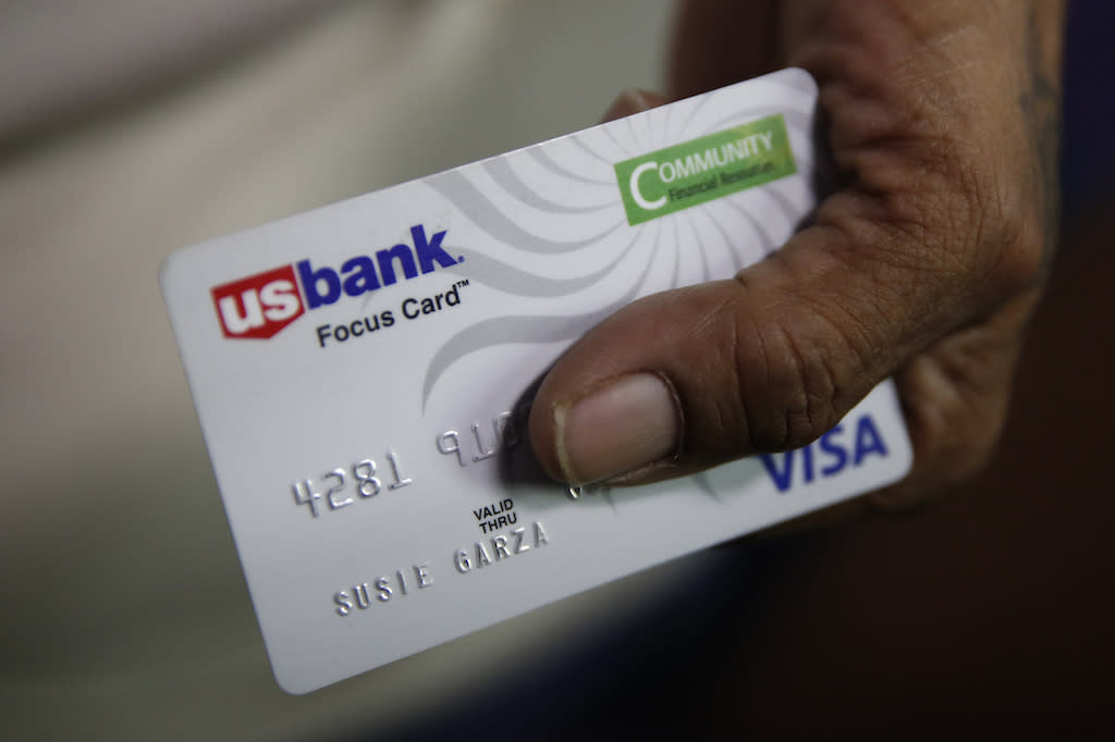 A woman displays a city-provided debit card she receives monthly through a trial program in Stockton, Calif.