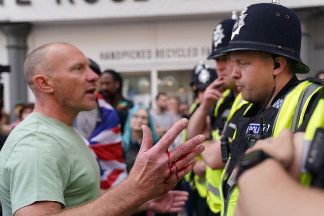 A man with blood on his hand speaks to a police officer during a protest in Nottingham's Market Square