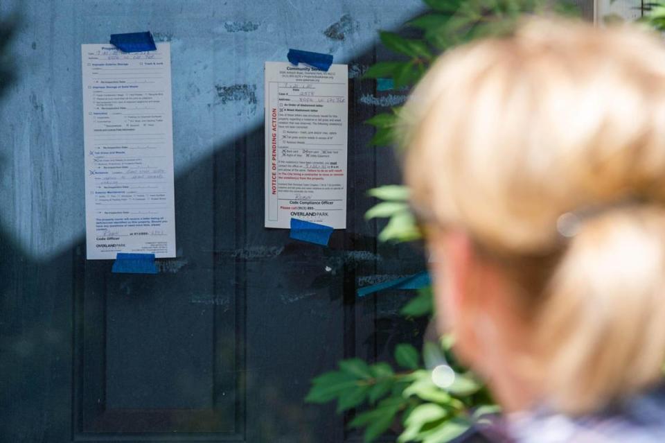 Neighbor Sheila Rodriguez looks over the violation stickers the city of Overland Park placed on the front door of the abandoned home of former Kansas City Chiefs player Tony Richardson.