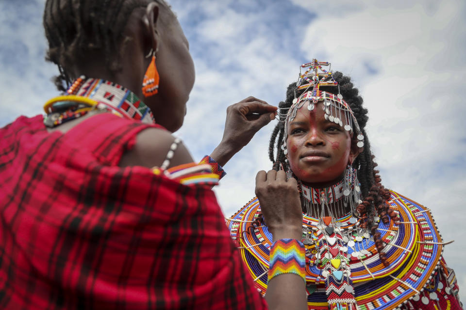 A Maasai woman adjusts the jewellery of another as they prepare to watch the Maasai Olympics in Kimana Sanctuary, southern Kenya Saturday, Dec. 10, 2022. The sports event, first held in 2012, consists of six track-and-field events based on traditional warrior skills and was created as an alternative to lion-killing as a rite of passage. (AP Photo/Brian Inganga)