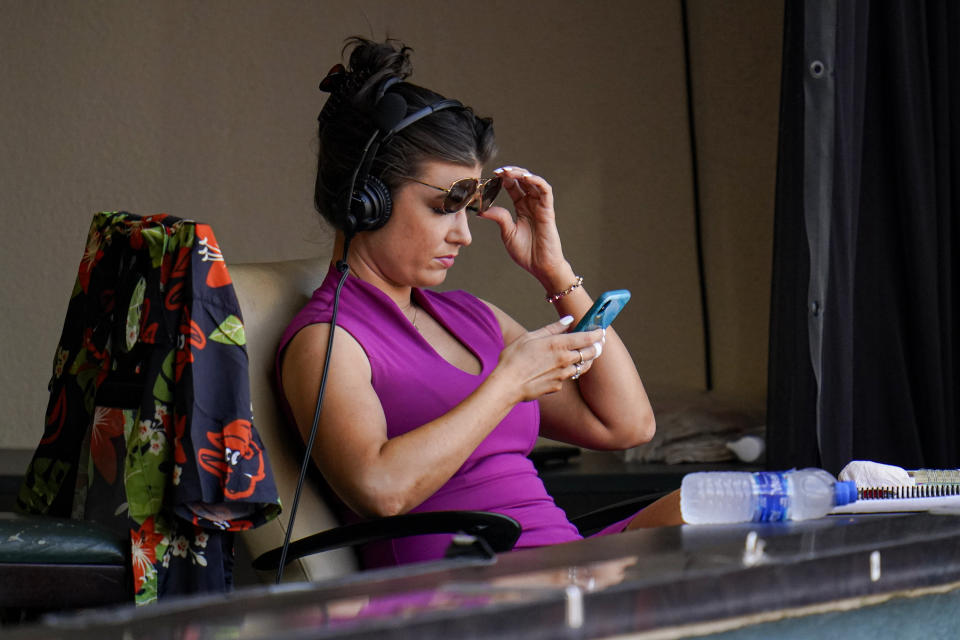 FILE - Melanie Newman, play-by-play broadcaster for the Baltimore Orioles, looks at her phone between innings during the fourth inning of a baseball game between the Baltimore Orioles and the Chicago White Sox in Baltimore, in this Saturday, July 10, 2021, file photo. Baltimore Orioles radio and TV announcer Melanie Newman was a part of the first all-woman broadcast crew for an MLB game earlier this season. On Wednesday, Sept. 29, 2021, she teams up with Jessica Mendoza on ESPN for the game between the San Diego Padres and Los Angeles Dodgers.(AP Photo/Julio Cortez, File)