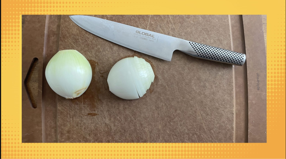 Global chef's knife on a cutting board with sliced onion