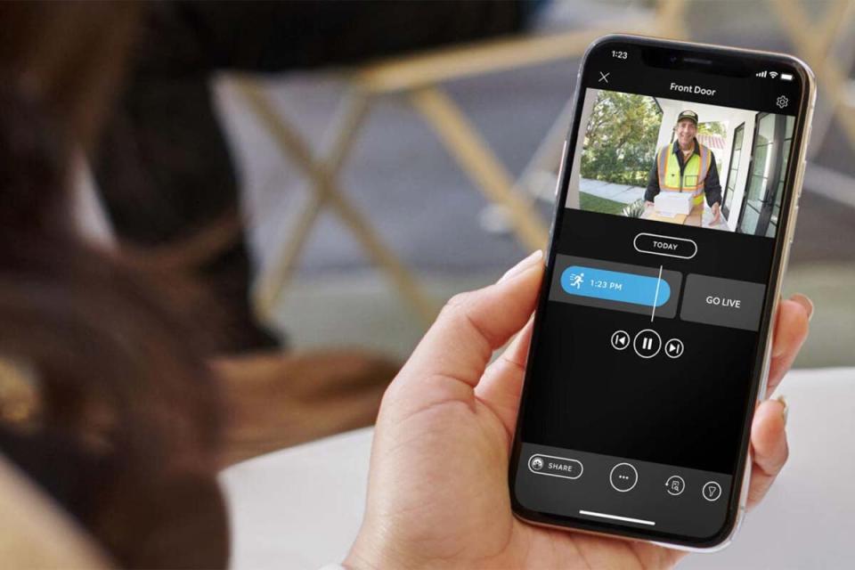 A woman watches security footage on her smart phone.