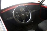 <p>A chunky steering wheel, and clear evidence of the car's original color being red.</p>