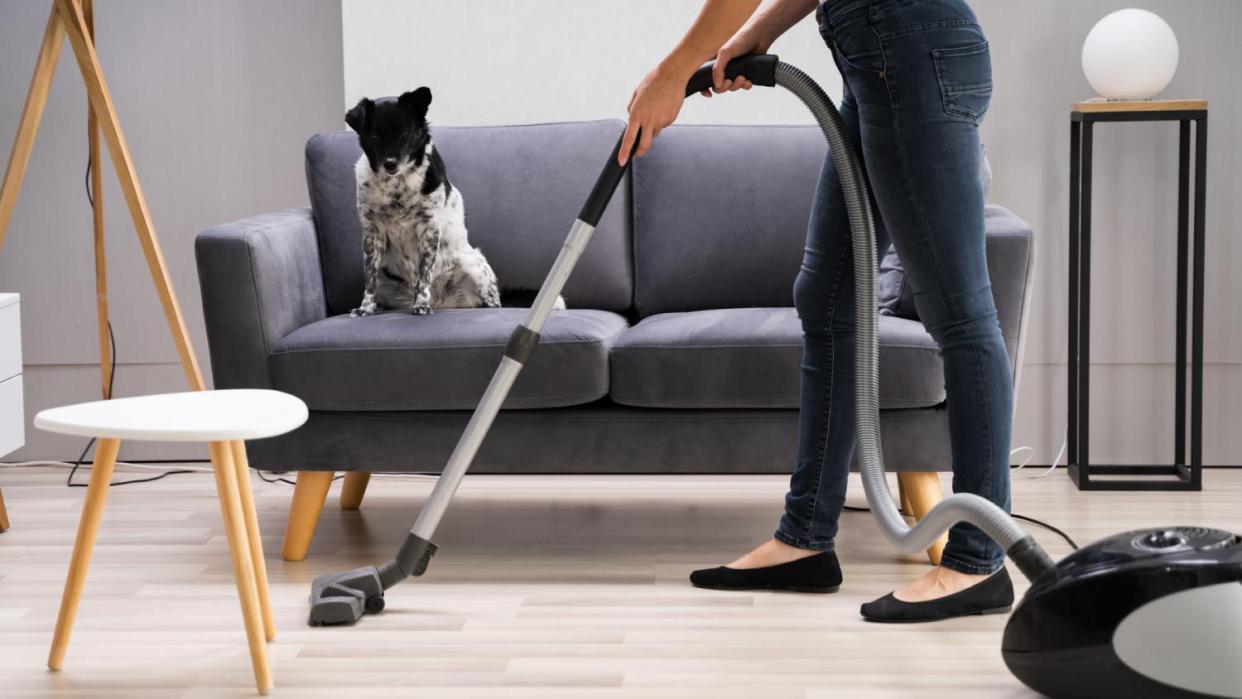 A woman cleaning floor with a vacuum cleaner