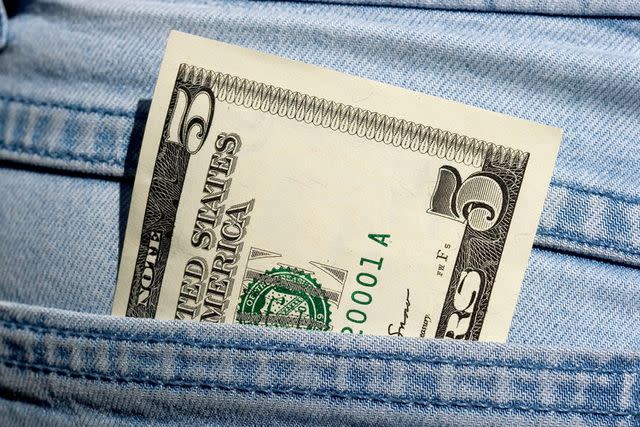<p>vandervelden/Getty</p> Stock image of a five dollar bill in a person's jean pocket